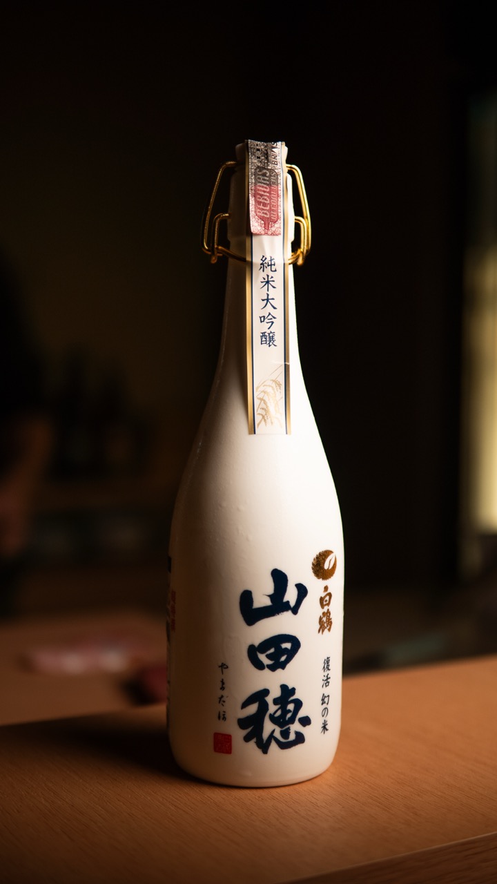Sake Yamada-ho em garrafa branca com caligrafia japonesa